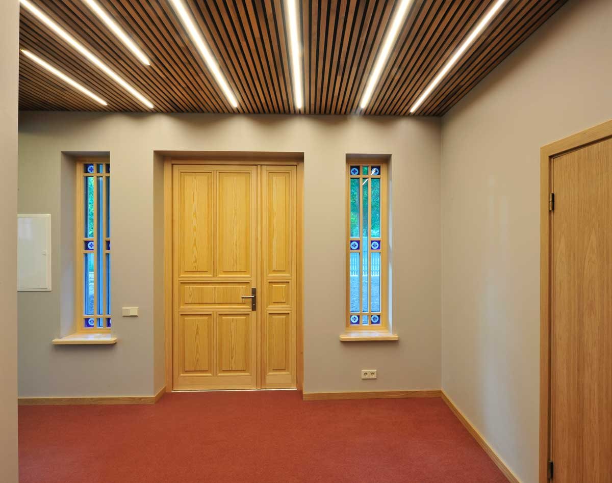 Hallway ceiling in thermo aspen slats with warm lighting and a wooden door