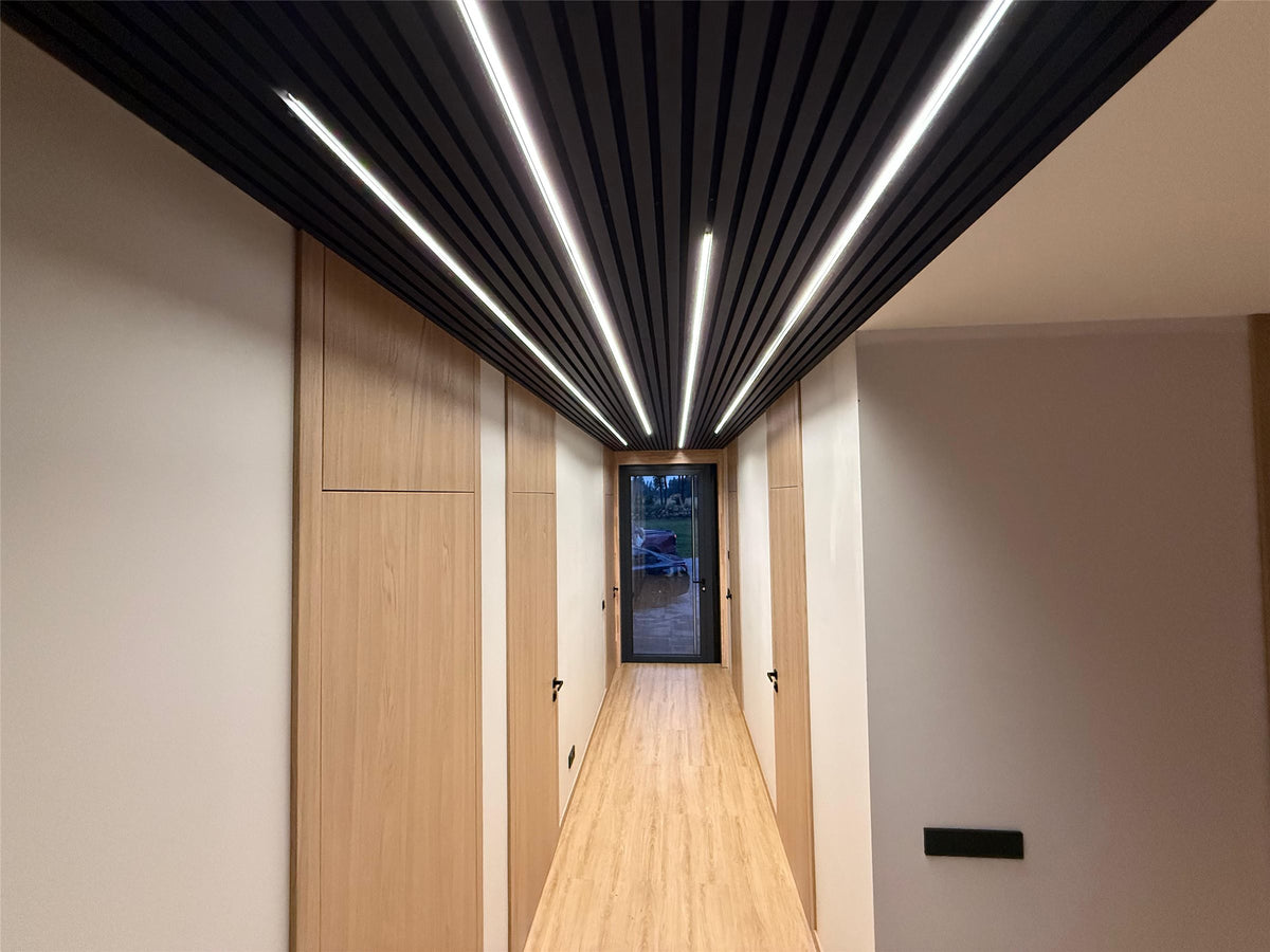 Corridor with an anthracite slat acoustic ceiling and linear lights