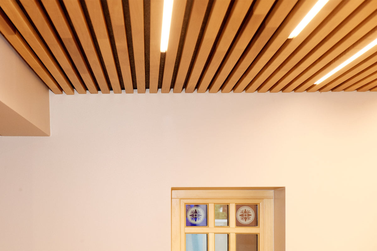 Thermo aspen slat ceiling with recessed light strips above a white wall