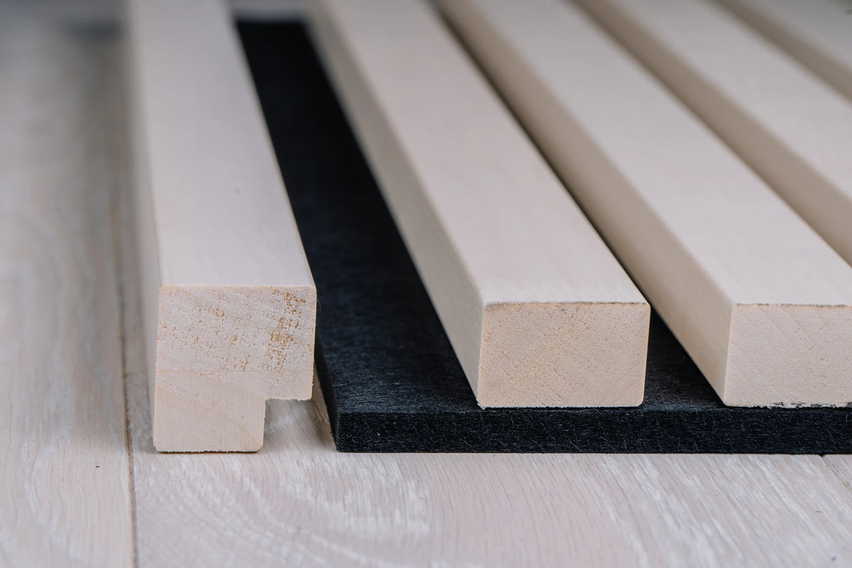 Close-up of the white end moulding profile next to white aspen slats on black felt