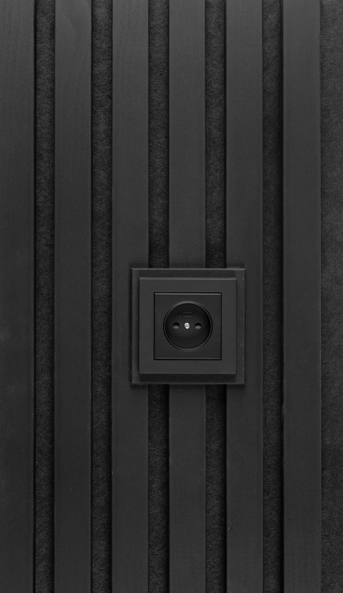 Anthracite plate around a black wall socket on anthracite aspen slats