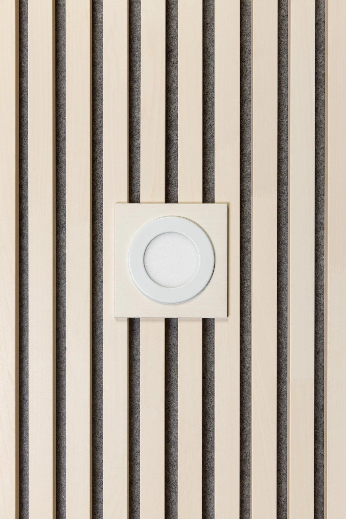 White universal plate with a round recessed light set into white aspen slats on grey felt